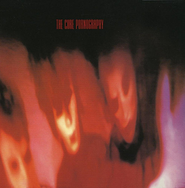 This image features the album cover of "Pornography" by The Cure, a vinyl LP released in 1982. The artwork is striking with its dark, blurred visages in shades of red and black, creating a haunting and intense visual effect that complements the album's dark and moody musical phase of the band.