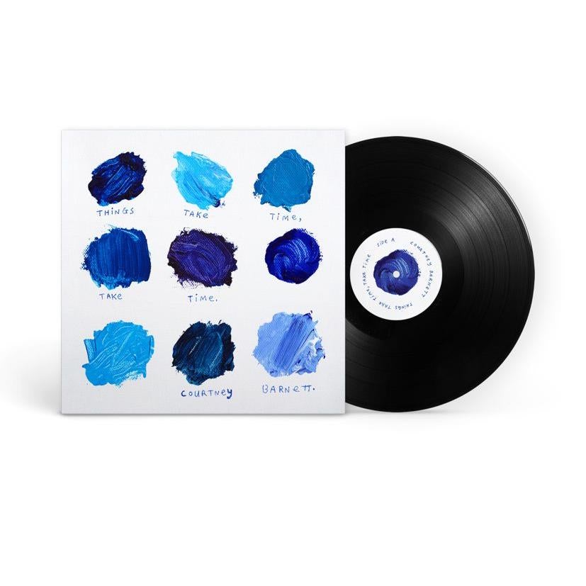 A vinyl LP of Courtney Barnett's album 'Things Take Time, Take Time' with a plain white cover featuring blue paint swatches and the album name.