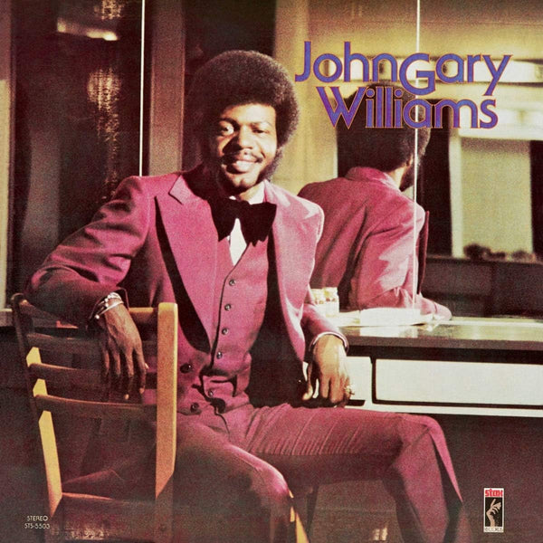 The cover image shows the artist, John Gary Williams, seated at a desk, wearing a suit and a bow tie, with his album title prominently displayed at the top.