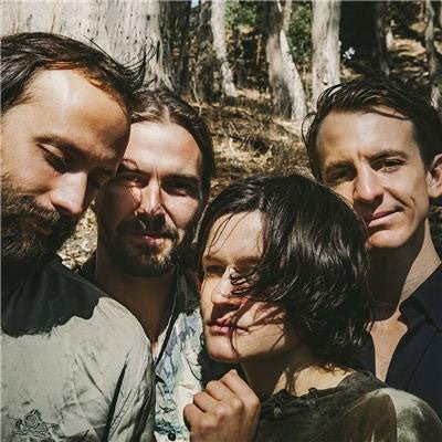 A group photo of the band Big Thief, with members posing informally outdoors.