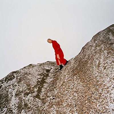 Reward vinyl LP by Cate Le Bon, experimental indie rock; with Cate wearing all red walking along a boulder